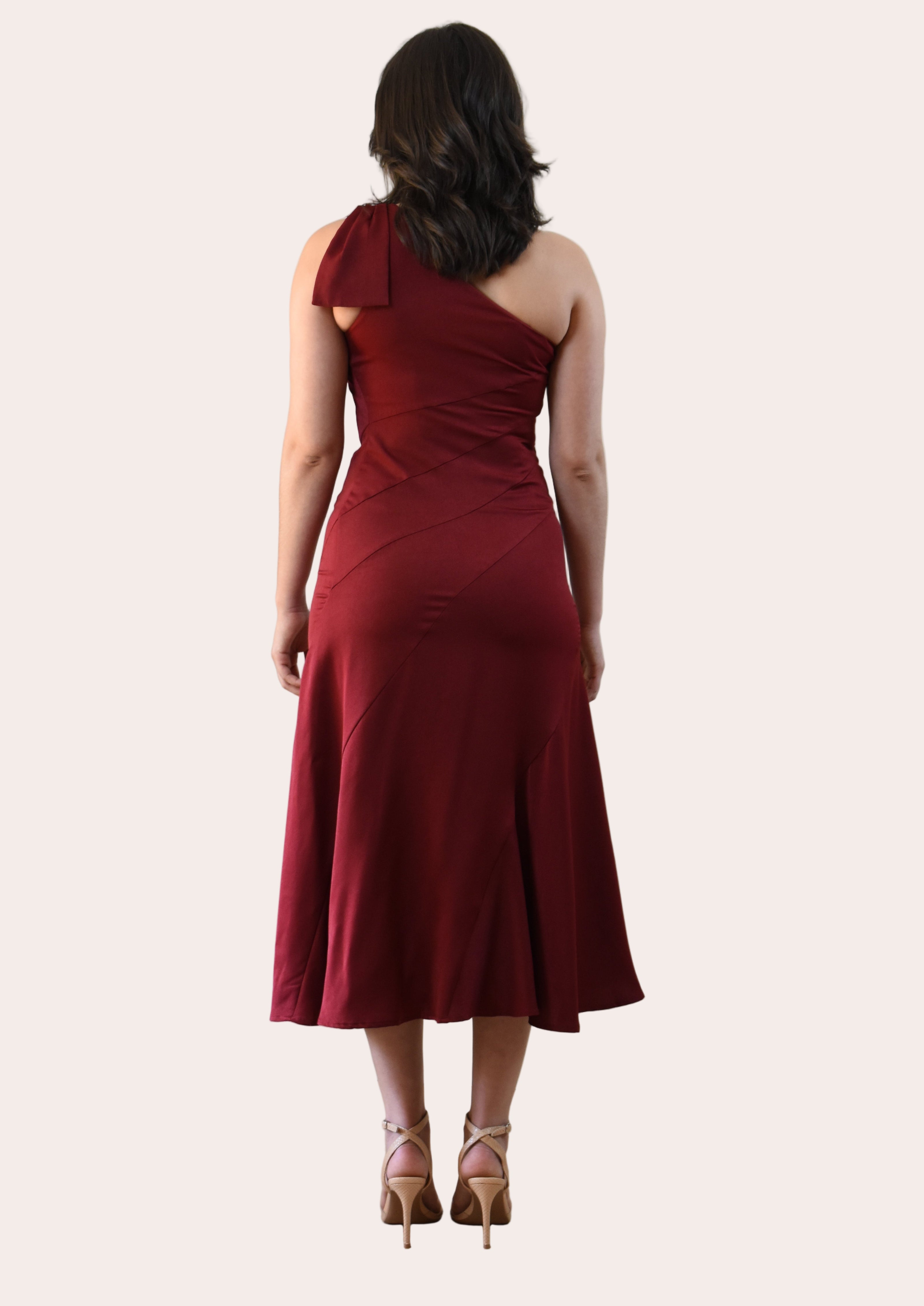 Cranberry Grace Dress with one-shoulder bow detail, slanted seamwork, and flared midi hem, designed for elegant movement, photographed on Soft Linen background.