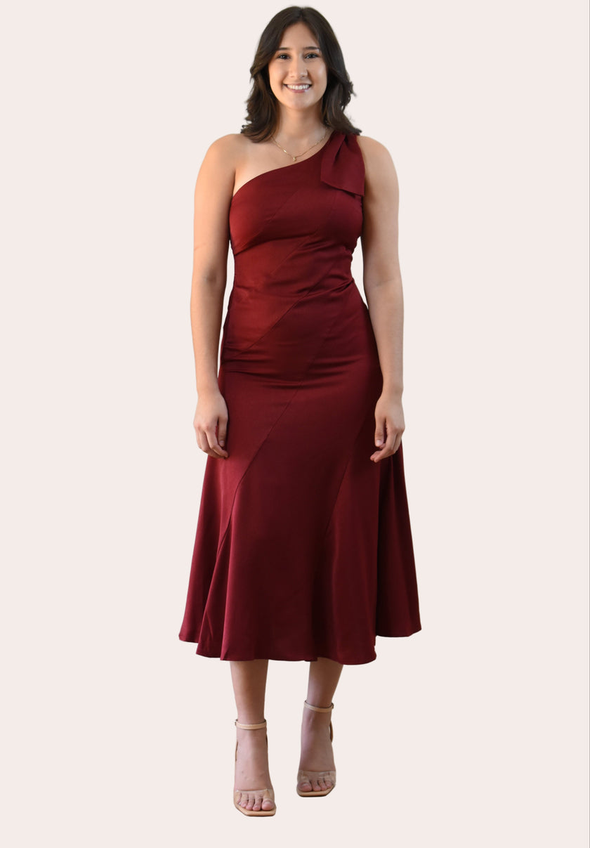 Cranberry Grace Dress with one-shoulder bow detail, slanted seamwork, and flared midi hem, designed for elegant movement, photographed on Soft Linen background.