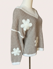 Mocha V-neck drop-shoulder sweater with floral appliqués and contrast trim at neckline, cuffs, and hem, photographed on a Soft Linen background for Justyna Grace Boutique.