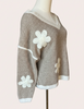 Mocha V-neck drop-shoulder sweater with floral appliqués and contrast trim at neckline, cuffs, and hem, photographed on a Soft Linen background for Justyna Grace Boutique.