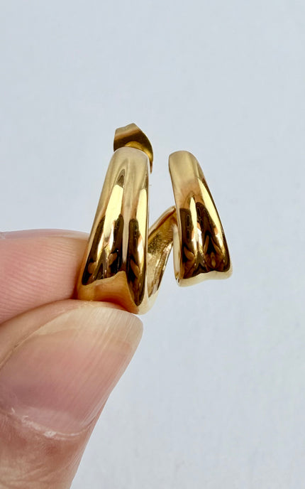 Hand holding double twist hoop earrings in 18k gold PVD over stainless steel showing dimensional twist detail