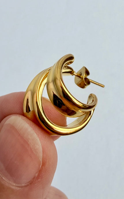 Double twist hoop earrings in hand showing size reference and 18k gold PVD finish over 316L stainless steel