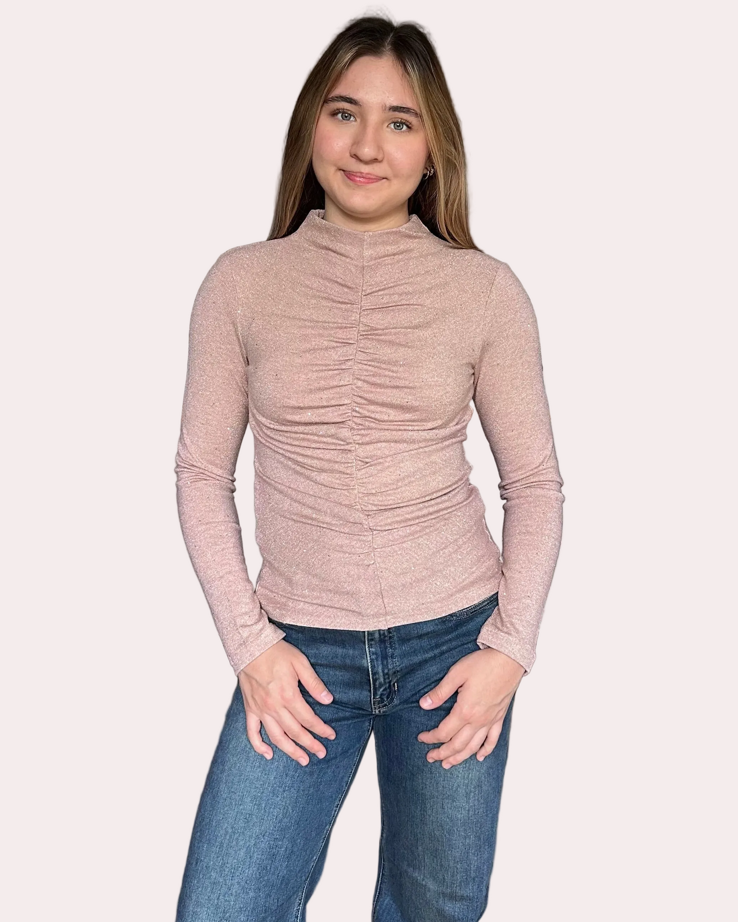 Woman wearing a ruched long-sleeve top and jeans on a white background