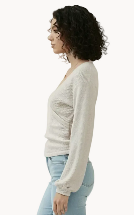 Woman wearing a light-colored sweater and light blue jeans on a white background