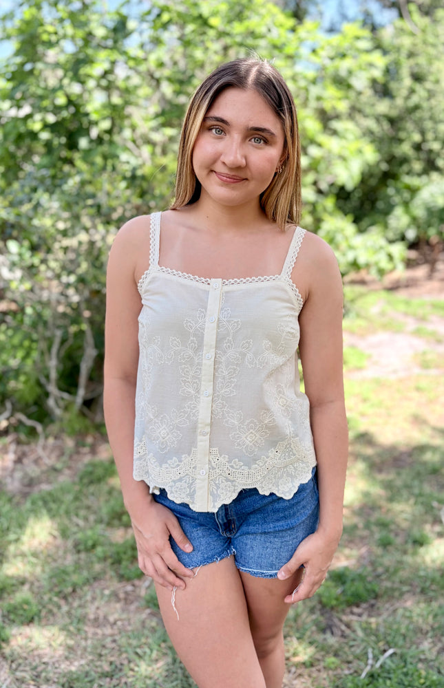 Front view of a white 100% cotton eyelet tank top with a square neckline and delicate button-front detail.