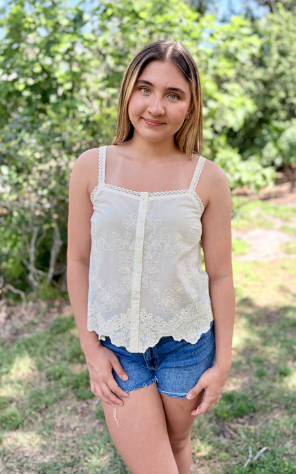 Front view of a white 100% cotton eyelet tank top with a square neckline and delicate button-front detail.