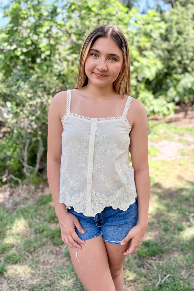 Front view of a white 100% cotton eyelet tank top with a square neckline and delicate button-front detail.