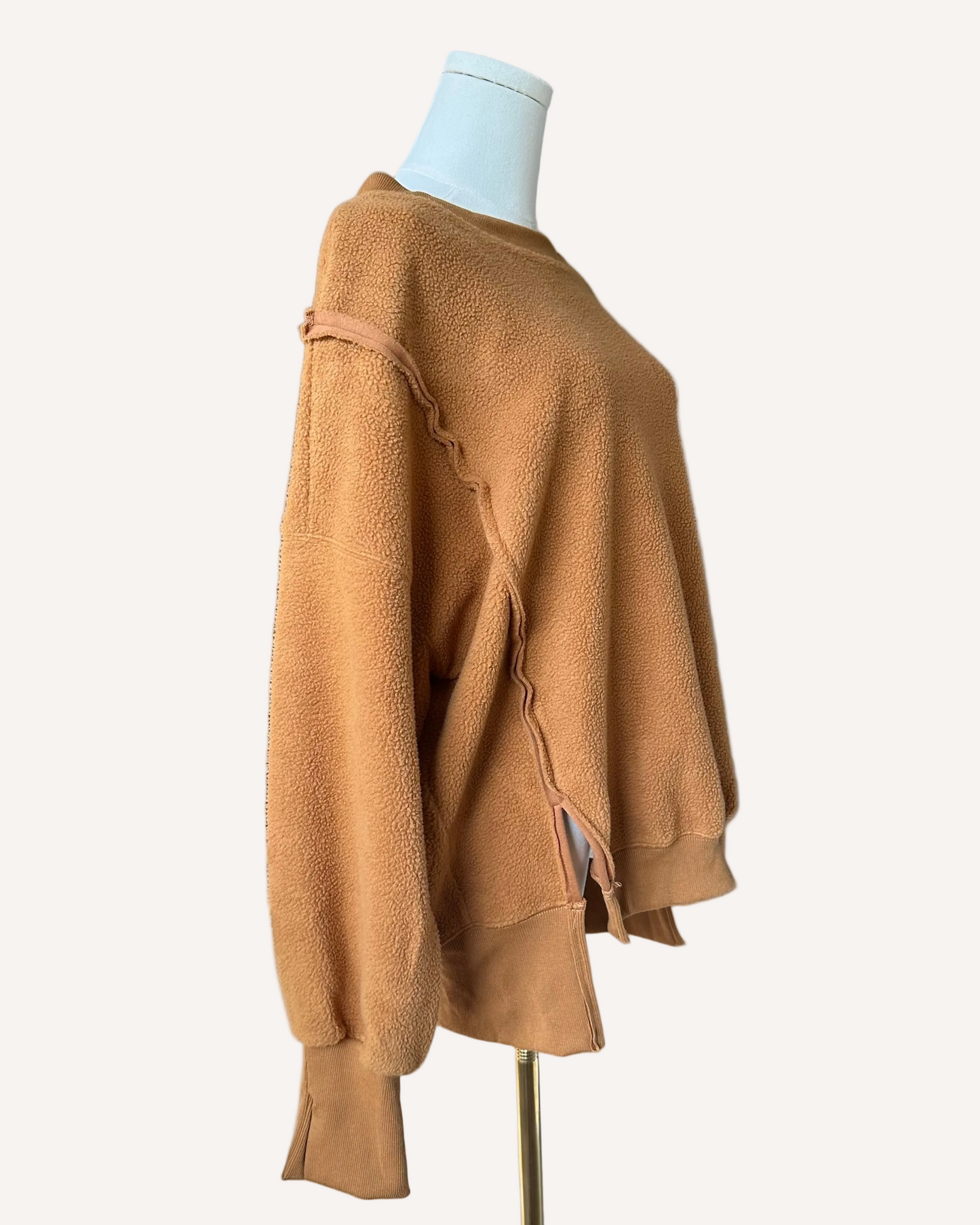 Soft fleece pullover with a relaxed fit, dropped shoulders, and reverse seam detailing, shown in a neutral tone against a clean soft-linen background.