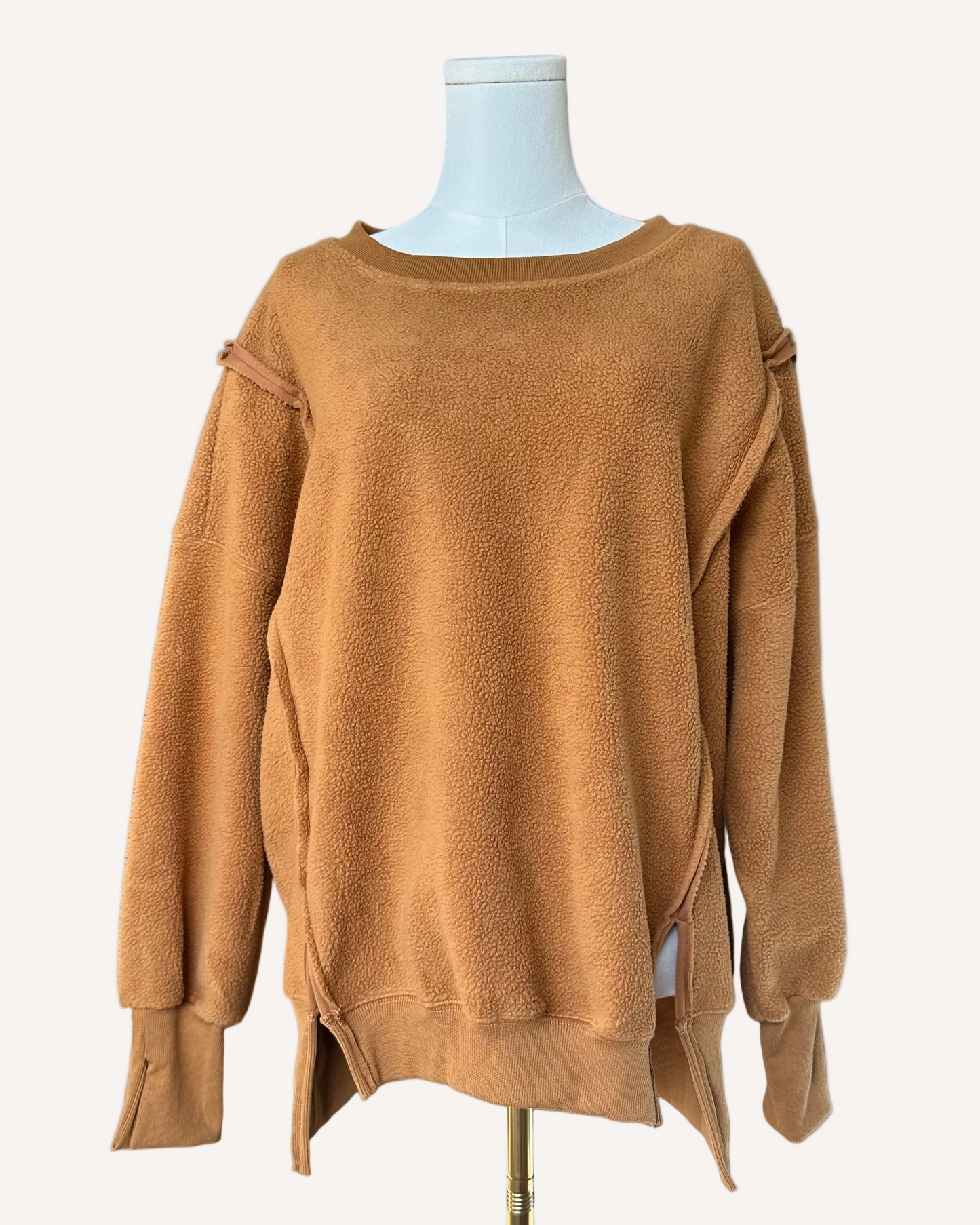 Soft fleece pullover with a relaxed fit, dropped shoulders, and reverse seam detailing, shown in a neutral tone against a clean soft-linen background.