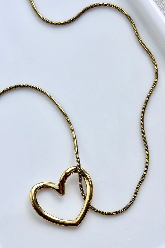 gold heart necklace on soft linen background with natural light, delicate everyday jewelry