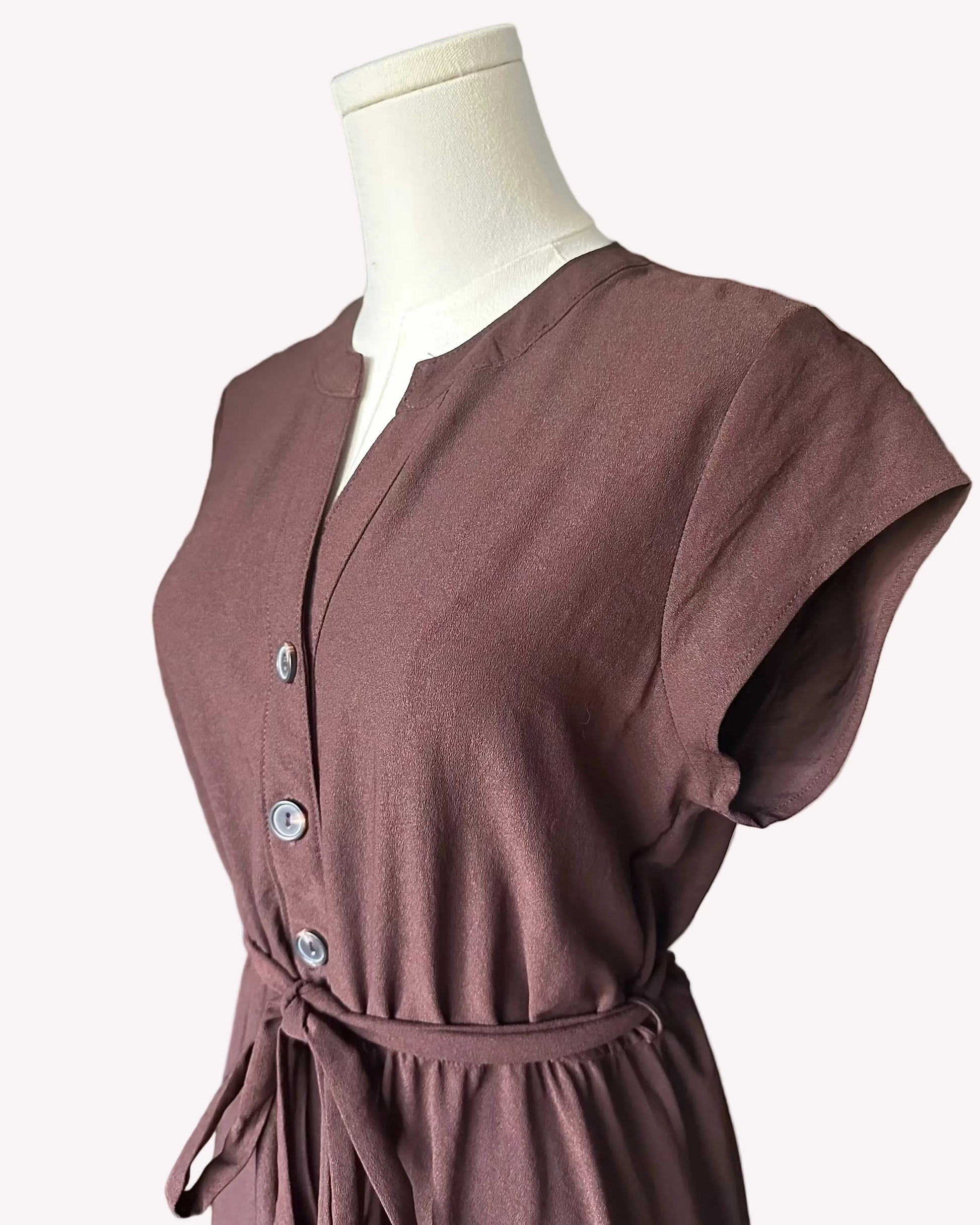 Brown dress on a mannequin against a light pink background