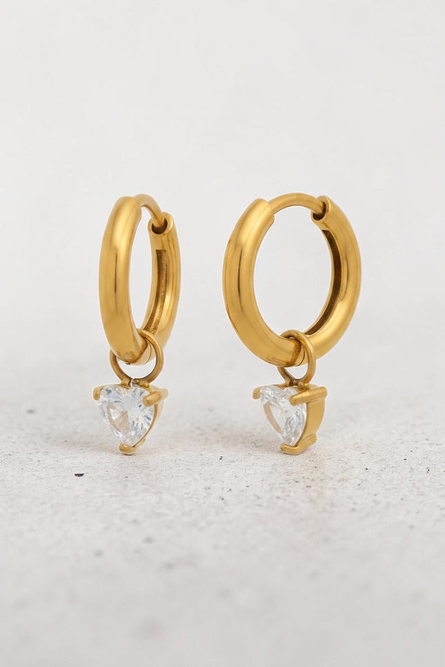Close-up of heart-shaped cubic zirconia crystal drop on gold hoop earring showing sparkle and 18k gold PVD finish