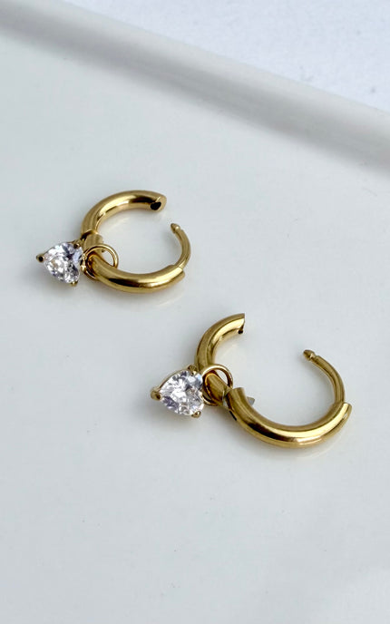 Gold heart crystal drop hoop earrings styled on jewelry dish showing feminine design and polished gold finish