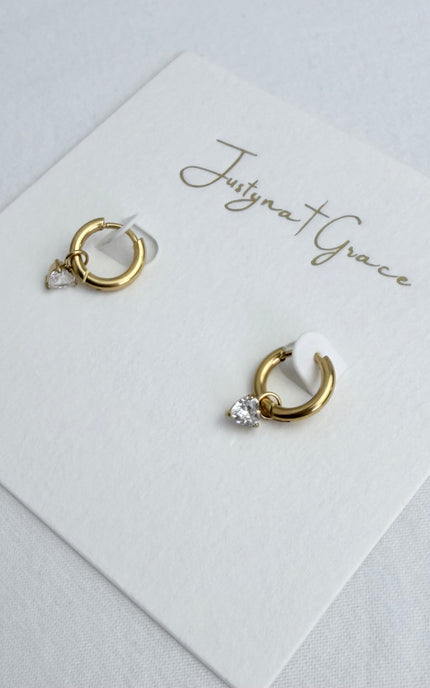 Flat lay of gold hoop earrings with heart-shaped crystal drop in 18k gold PVD over 316L stainless steel