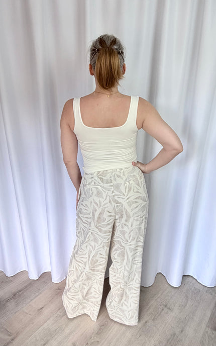 Back view of tropical leaf print pants featuring an elastic waistband and straight leg silhouette.