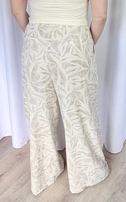 Back view of tropical leaf print pants featuring an elastic waistband and straight leg silhouette.