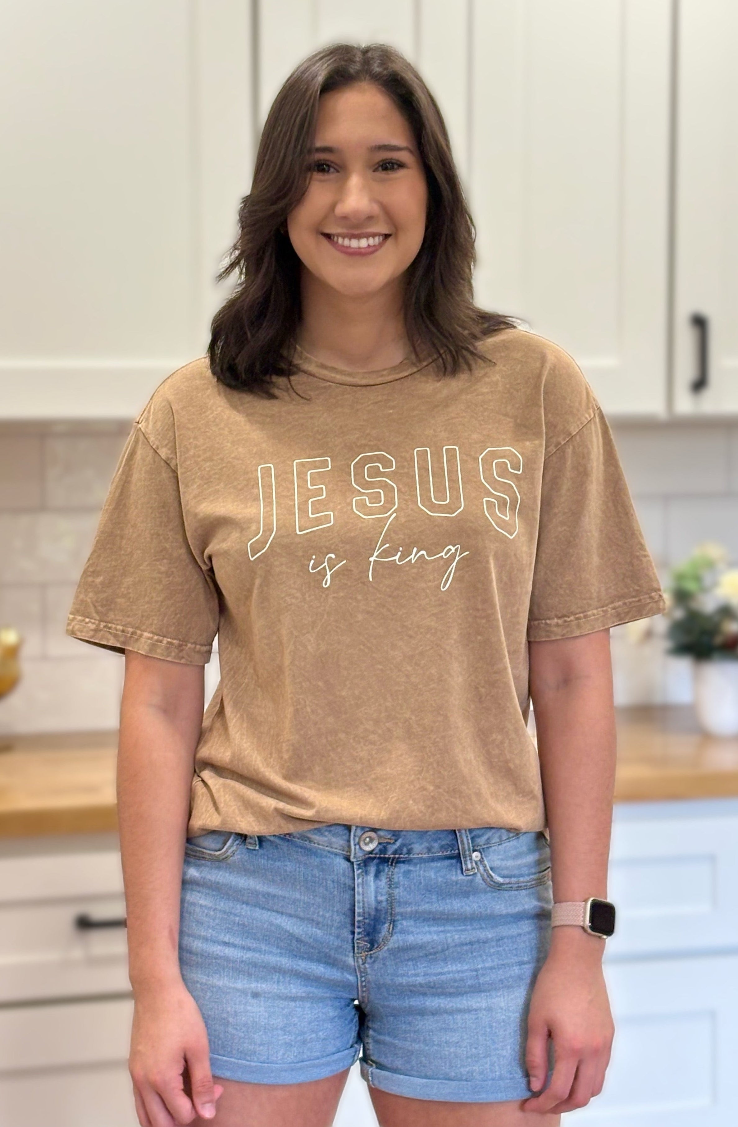 Gold mineral-wash “Jesus Is King” graphic tee with relaxed unisex fit and vintage garment-dyed finish.
