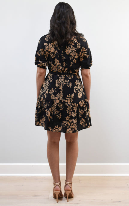 Kelly Mini Dress on soft linen background, featuring a ruffle neckline with tie and lightweight cotton–rayon fabric.