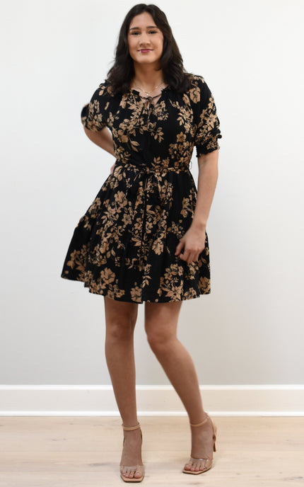Kelly Mini Dress on soft linen background, featuring a ruffle neckline with tie and lightweight cotton–rayon fabric.