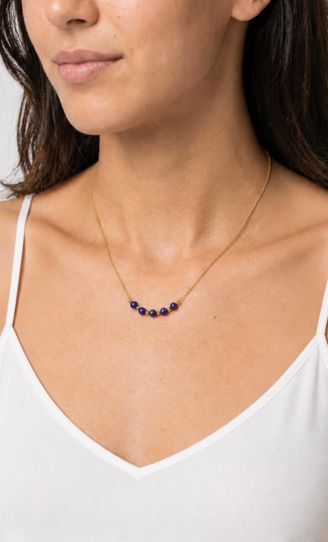 A three-quarter angled profile view of the model in natural light, showcasing the vibrant pop of the deep blue lapis beads against a warm-weather outfit.