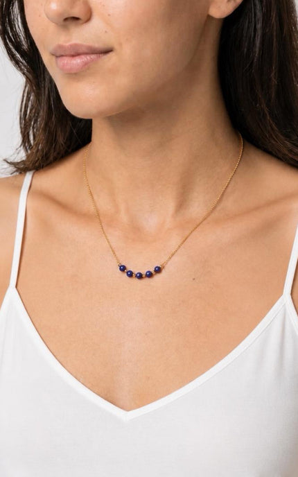 A three-quarter angled profile view of the model in natural light, showcasing the vibrant pop of the deep blue lapis beads against a warm-weather outfit.