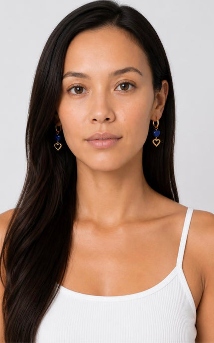 Front portrait view of a model wearing the Lapis Lazuli Double Heart Hoop Earrings from Justyna Grace Boutique, illustrating how the statement charms frame the face.
