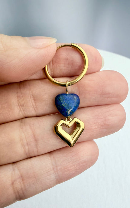 A tight, handheld shot of the lapis lazuli heart hoop earrings in a palm, perfectly displaying the scale of the 19.8mm gold hoops and the romantic, layered heart charms in warm, natural light.