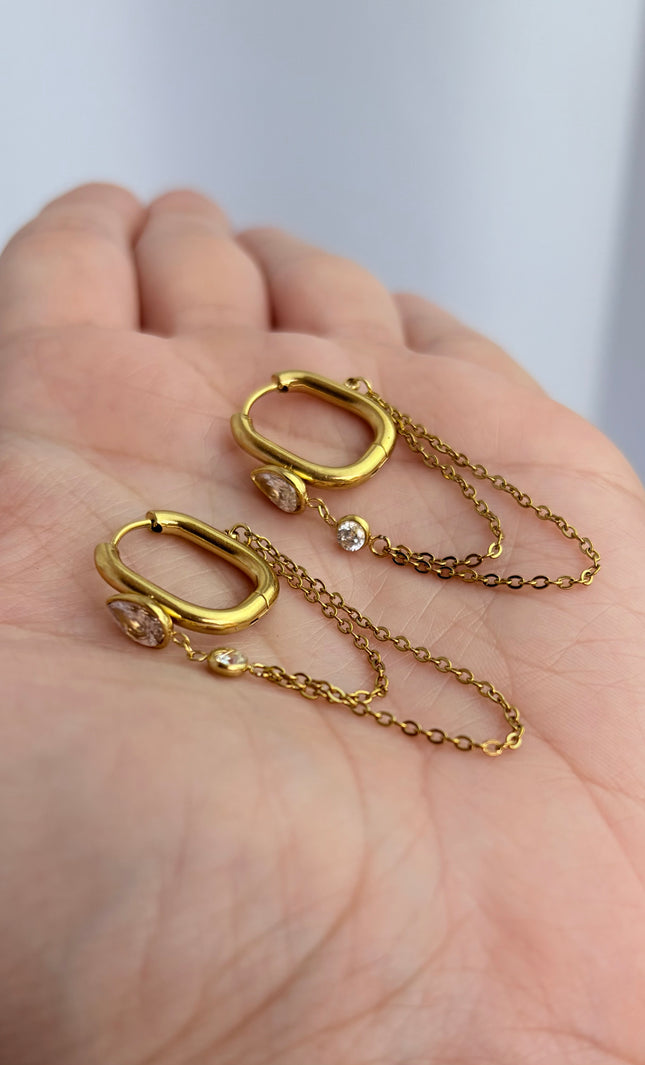 Gold drop hoop earrings with layered chain detail held in hand showing scale, drop length, and 18k gold PVD finish