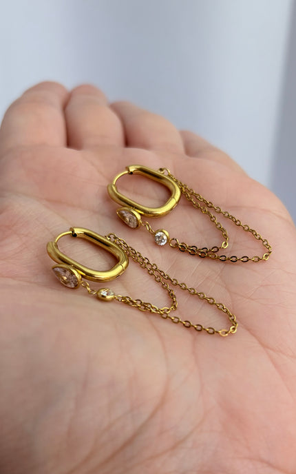 Gold drop hoop earrings with layered chain detail held in hand showing scale, drop length, and 18k gold PVD finish