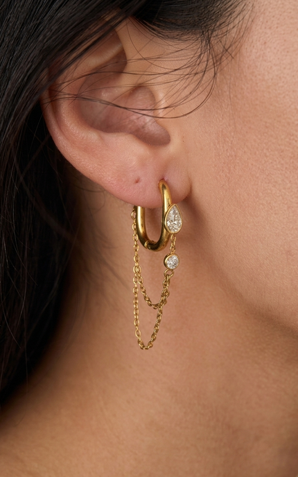 Layered chain drop hoop earrings worn on ear showing feminine silhouette and light-catching movement detail
