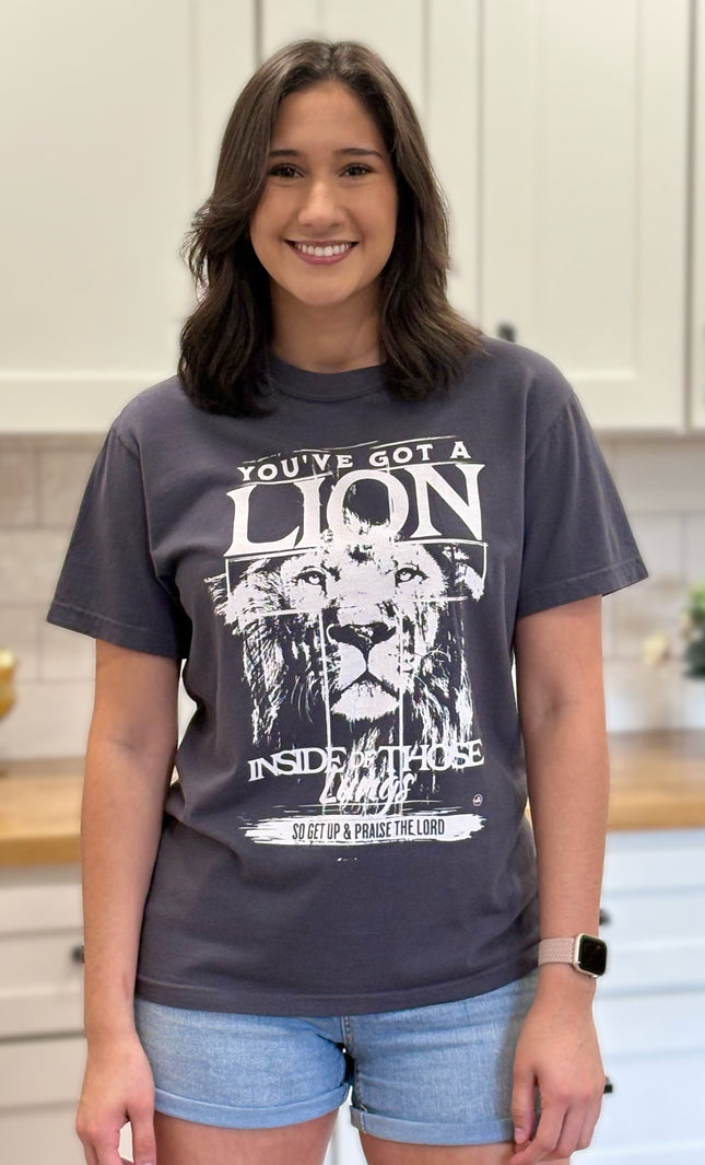 Graphite Comfort Colors tee with “You’ve Got a Lion Inside Those Lungs” worship lyric design, unisex fit and vintage finish.