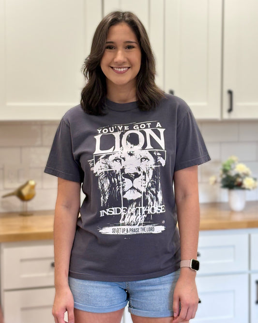 Graphite Comfort Colors tee with “You’ve Got a Lion Inside Those Lungs” worship lyric design, unisex fit and vintage finish.