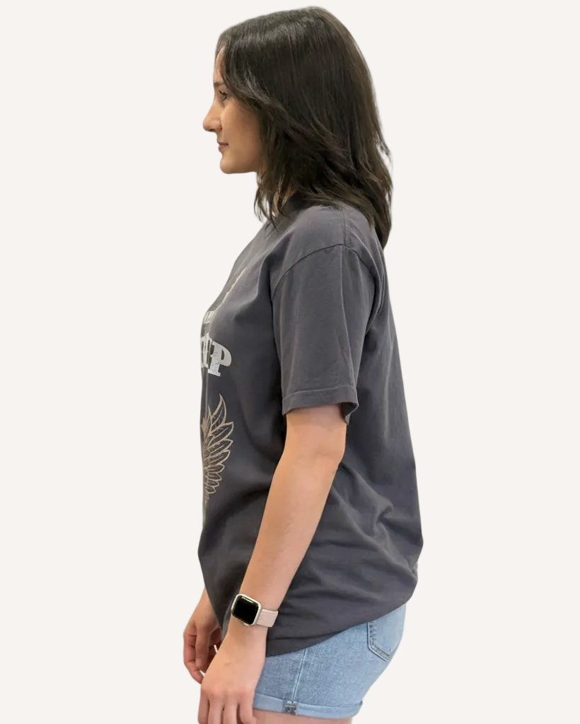 Woman wearing a dark gray t-shirt with a logo on a plain background