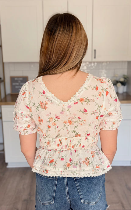 Model wearing Maribel floral eyelet peplum top with lace trim and bubble sleeves
