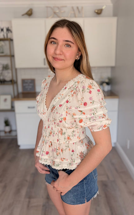 Model wearing Maribel floral eyelet peplum top with lace trim and bubble sleeves