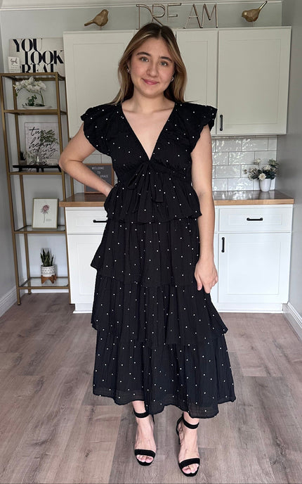 Black polka dot tiered midi dress featuring short sleeves and flowing silhouette