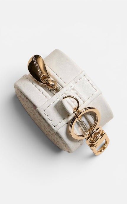 Side profile of the round floral jewelry case, highlighting its 1.5-inch depth, the all-around gold zipper closure, and a functional keychain clip attached to the side.