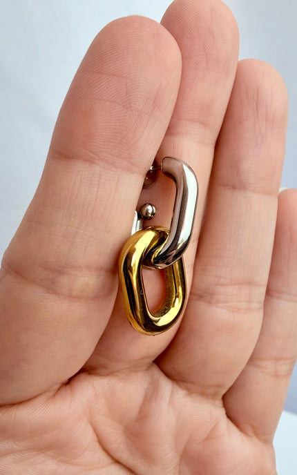 Mixed metal gold and silver link earrings held in hand showing scale, link design, and 18k gold PVD finish