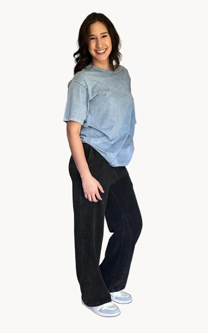 Woman wearing a light blue shirt and dark pants on a white background