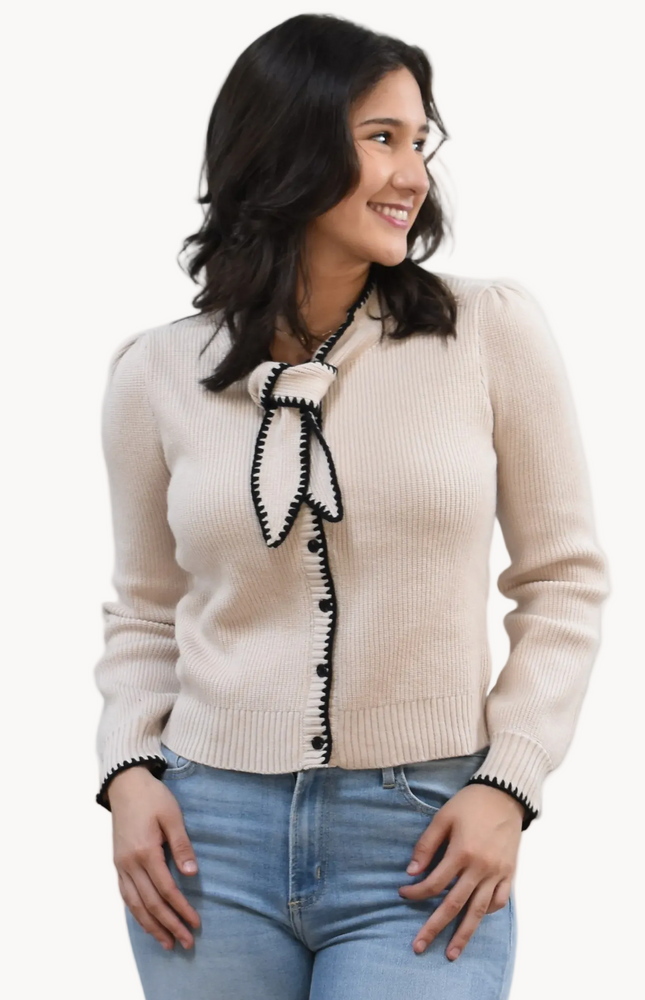 Petite Bow Knit Cardi on soft linen background, featuring a contrast-knit body and delicate bow detail at the neckline.