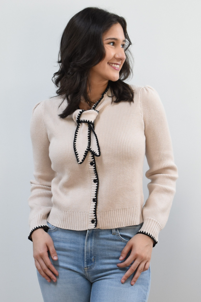 Petite Bow Knit Cardi on soft linen background, featuring a contrast-knit body and delicate bow detail at the neckline.