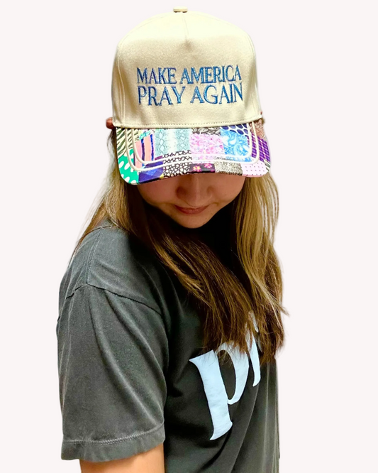 Person wearing a cap with 'MAKE AMERICA PRAY AGAIN' text on a plain background