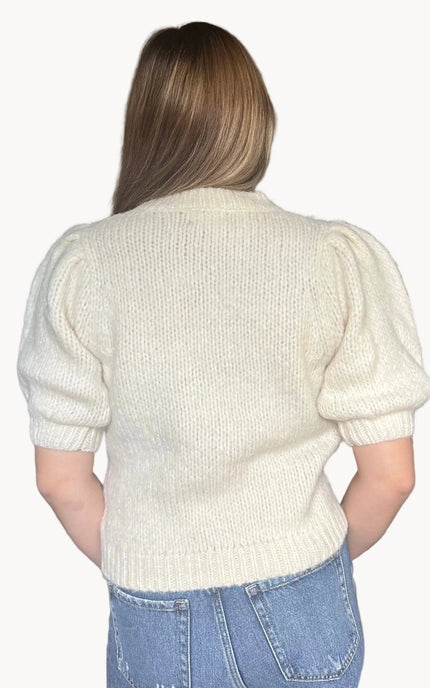 Model wearing a soft knit puff sleeve sweater with fitted cuffs and a flattering silhouette, styled for an effortlessly polished look.