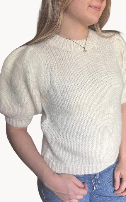 Model wearing a soft knit puff sleeve sweater with fitted cuffs and a flattering silhouette, styled for an effortlessly polished look.