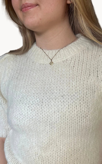 Model wearing a soft knit puff sleeve sweater with fitted cuffs and a flattering silhouette, styled for an effortlessly polished look.