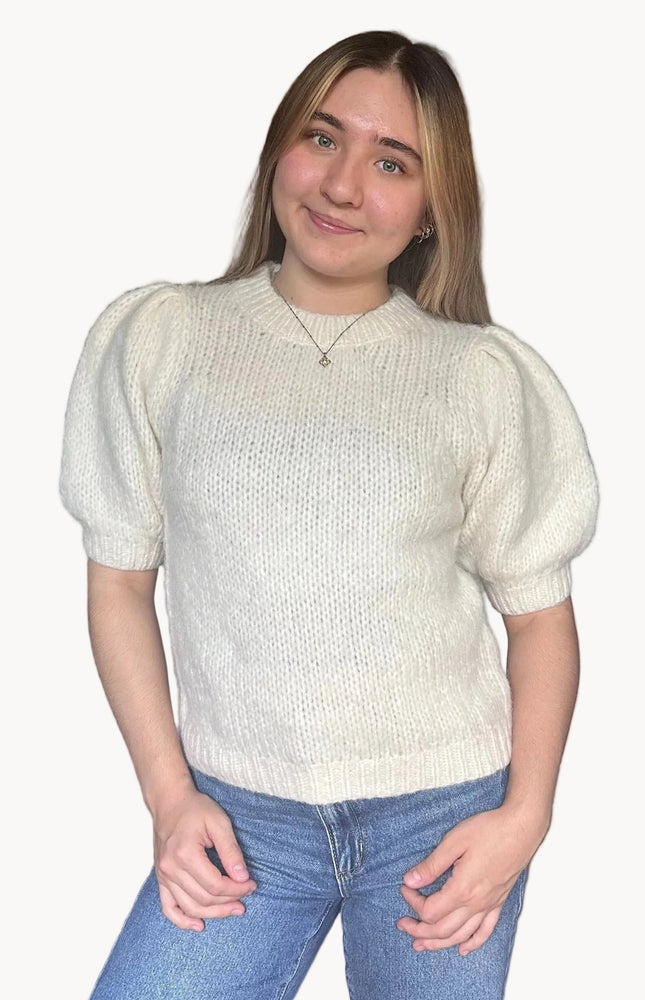 Model wearing a soft knit puff sleeve sweater with fitted cuffs and a flattering silhouette, styled for an effortlessly polished look.