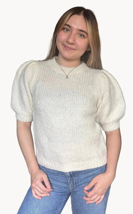 Model wearing a soft knit puff sleeve sweater with fitted cuffs and a flattering silhouette, styled for an effortlessly polished look.