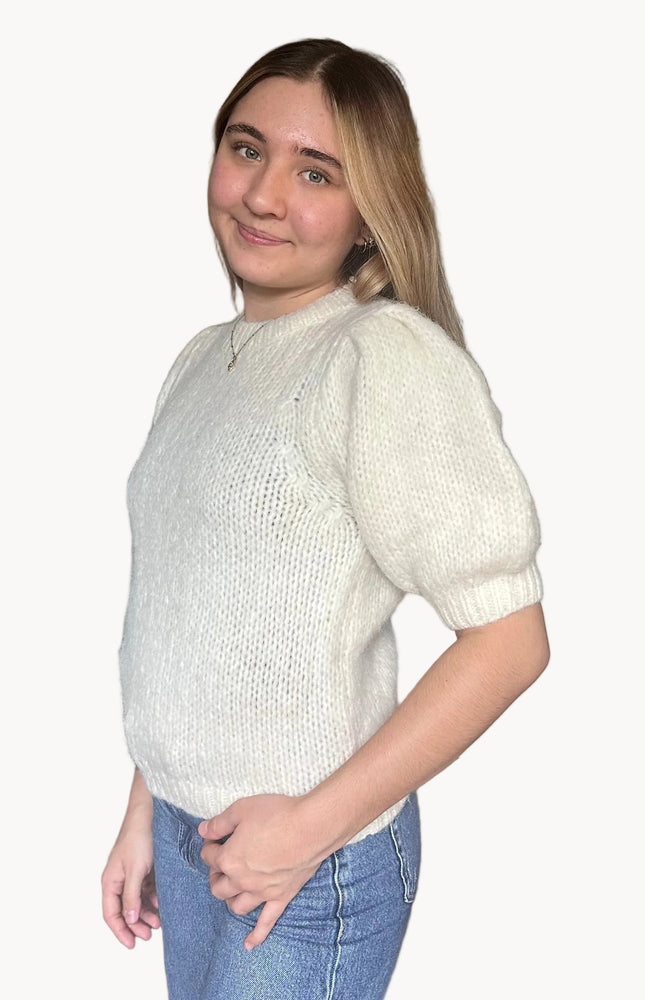 Model wearing a soft knit puff sleeve sweater with fitted cuffs and a flattering silhouette, styled for an effortlessly polished look.