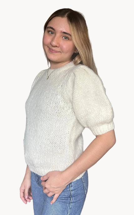 Model wearing a soft knit puff sleeve sweater with fitted cuffs and a flattering silhouette, styled for an effortlessly polished look.