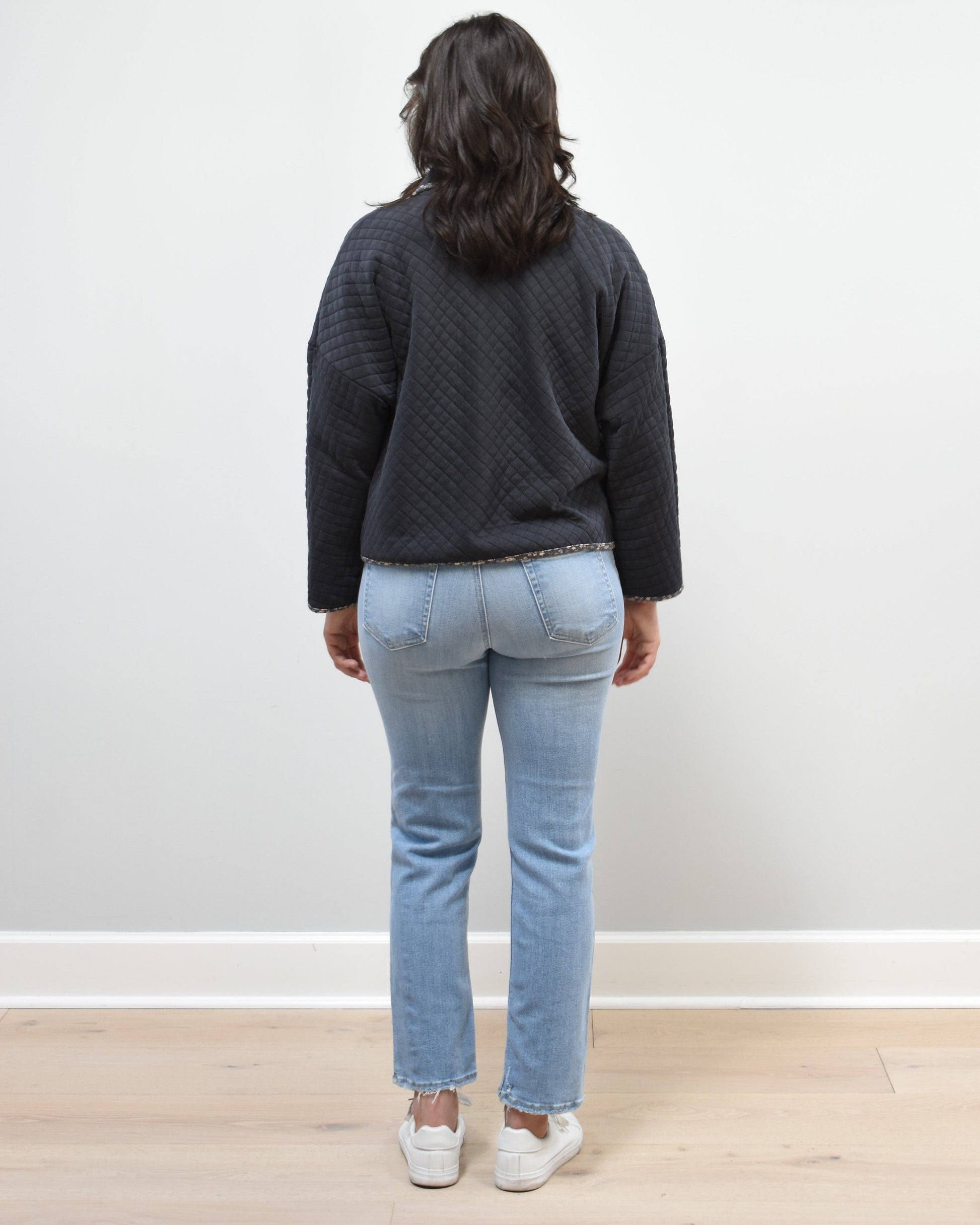 Back view of the quilted floral contrast zip-up jacket showing the mock neck, side pockets, and feminine detailing.